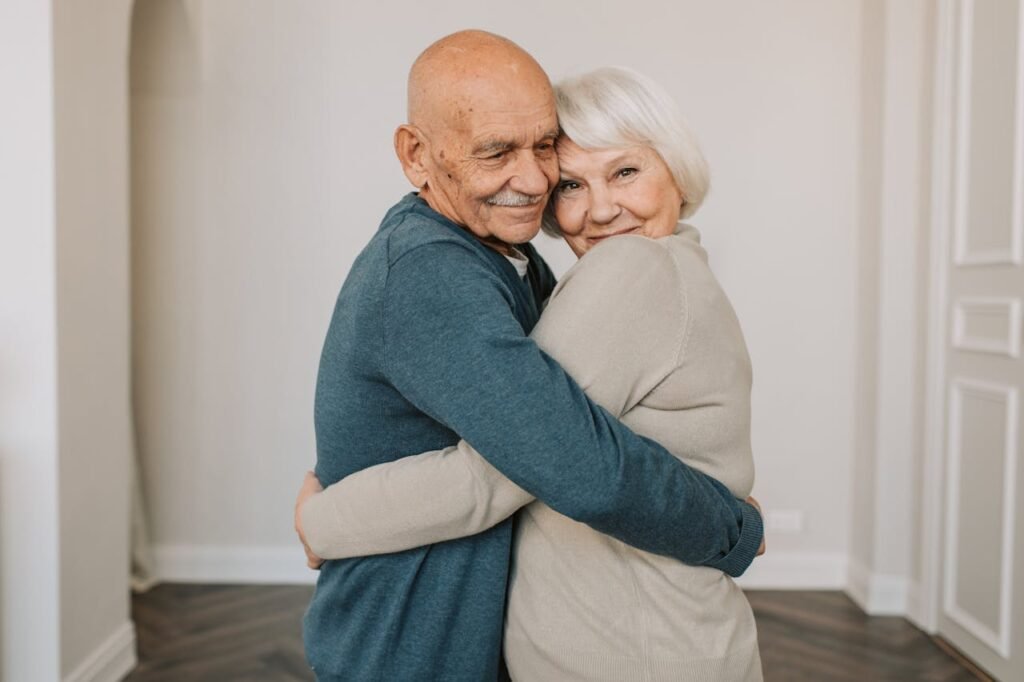Senior couple hugging warmly indoors, showcasing love and happiness.